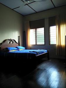 1 dormitorio con 1 cama con sábanas azules y 2 ventanas en Villasayang Homestay en Mersing