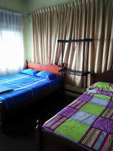 a bedroom with two beds and a window with curtains at Villasayang Homestay in Mersing
