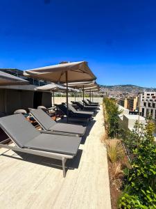 a row of lounge chairs with umbrellas on a roof at Moon & Sun Funchal in Funchal
