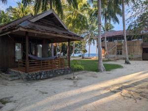 a building on the beach with palm trees at Fadhila Cottages Togean Dive Resort in Katupa