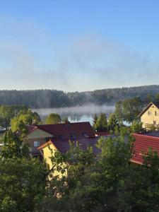 a group of houses and trees with fog in the background at Kłączyn in Kłaczno