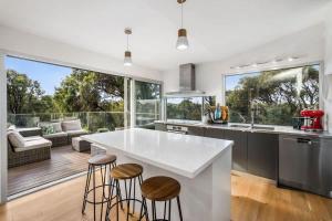 a kitchen with a large white counter and stools at Coastal Tree Top Views in Aireys Inlet