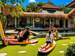 a group of people sitting on surfboards in the grass at Waiwas Hostel in Kuta Lombok