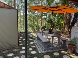 a picnic table with an umbrella and a bench at Kholiwe 1 - 4 sleeper glamping in a forest in Port Edward