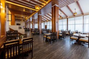 a dining room with tables and chairs and windows at DANFÉ Lodge Halesi in Lamidanda