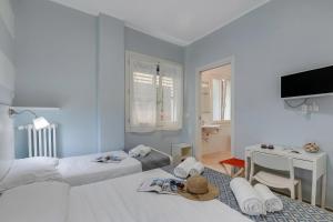 a bedroom with two beds and a desk and a television at Hotel Del Golfo in Laigueglia