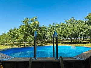 a swimming pool with a wooden deck and afficiencyivedivedivedivedivedived at Gîte La Chaumière avec Piscine in Nailhac