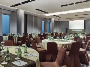 a conference room with tables and chairs and a screen at Novotel Karawang in Karawang +57 photos
