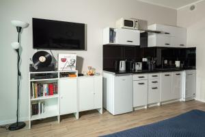 a kitchen with white cabinets and a tv on the wall at Sky tower space in Katowice