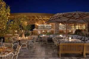 an outdoor patio with tables and chairs and an umbrella at Santa Marina, A Luxury Collection Resort, Mykonos in Ornos