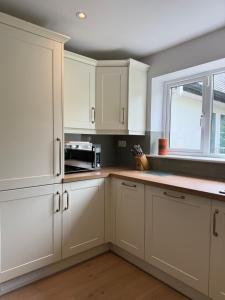 a white kitchen with white cabinets and a window at The Nook County Dublin in Dublin