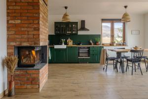 a kitchen with green cabinets and a brick fireplace at Widokówka in Wetlina