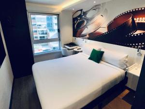 a bedroom with a white bed and a window at ibis Styles Montevideo Biarritz in Montevideo