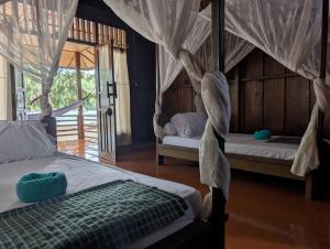 a bedroom with two beds with mosquito nets at Fadhila Cottages Togean Dive Resort in Katupa