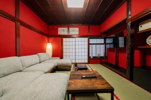 a living room with red walls and a couch and a table at 金沢町家 凛 in Kanazawa