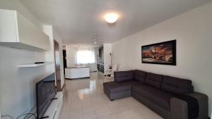 a living room with a couch and a flat screen tv at Villa a schiera con uso piscina in Aprilia Marittima
