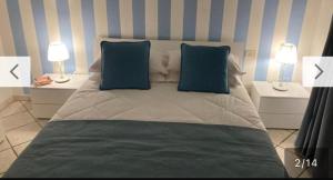 a bedroom with a bed with blue pillows and two lamps at Casa Annacarla in Noci