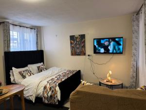 a bedroom with a bed and a tv on the wall at Sunrise Hills BNB in Ngong