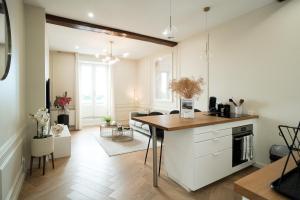a kitchen with white cabinets and a table in it at Le Lamartine - Vue Saône - Hypercentre in Mâcon