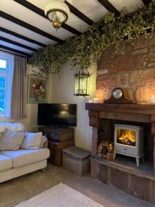 a living room with a fireplace and a couch and a tv at Spring Cottage in Hoylake