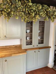 a kitchen with white cabinets with flowers on top at Spring Cottage in Hoylake +6 photos
