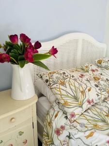 a white bed with a vase of flowers on a table at Spring Cottage in Hoylake