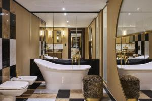 a bathroom with two toilets and a tub and a sink at Hotel Experior Boutique - Destigo Hotels in Krakow