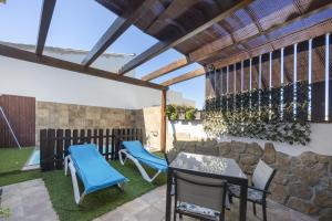 a patio with chairs and tables and a stone wall at Casa El Duque Zaira in Vejer de la Frontera