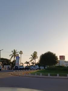 a street with cars parked in a parking lot with palm trees at AP Museu Maputo in Maputo