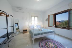 a white bedroom with a bed and a large window at Lenaki House in Ayía Kiriakí