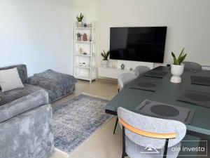 a living room with a table and a couch at Green Coast 153a - by Ale Investa in Palasë