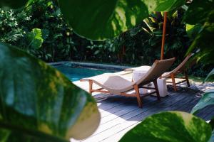 two chairs and a table next to a swimming pool at Villa Caz a Bali in Canggu