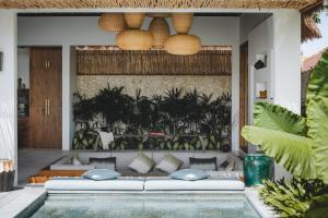a living room with a couch and a swimming pool at Villa Caz a Bali in Canggu