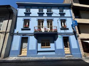 a blue building with flowers in the windows at Pension Alver - El Refugio del Artista in Cudillero
