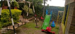 a group of swings in a yard with a house at Pine Breeze Getaway Lukenya in Athi River