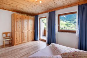 ein Schlafzimmer mit einem Bett und einem großen Fenster in der Unterkunft Pirchahof in Martell