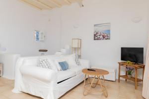 a white living room with a white couch and a table at Cycladic Boungainvillea Home in Kalafatis