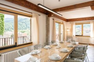 a long table in a room with chairs and windows at Majordoms Art in Sant Feliu de Pallerols