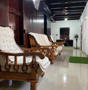 a row of wooden chairs sitting in a room at Heritage Haven in Changanācheri