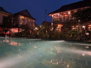 a swimming pool in front of some buildings at night at The MD Ba Vi Retreat in Ba Vì