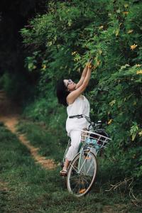 a woman is picking fruit from a tree on a bike at The MD Ba Vi Retreat in Ba Vì