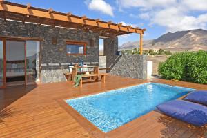 a villa with a swimming pool on a wooden deck at Casa San Luis in Pájara