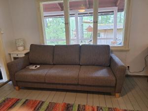 a brown couch in a living room with a window at Kalliotupa in Haapakylä