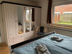 ein Schlafzimmer mit einem Bett, einem Stuhl und einem Fenster in der Unterkunft Petit in Hatten