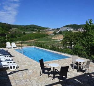 a swimming pool with tables and chairs next to a swimming pool at Just Joy Apartman in Vrdnik