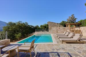 a pool with chaise lounge chairs and a swimming pool at Villa Iremia in Nísi