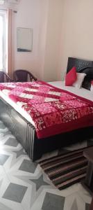 a bedroom with a bed with a red blanket on it at Pragya inn hotel Haldwani in Haldwāni