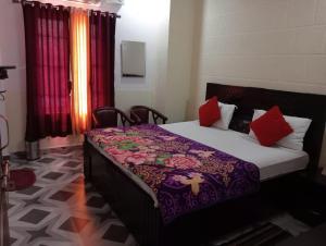 a bedroom with a bed with a purple blanket and red pillows at Pragya inn hotel Haldwani in Haldwāni