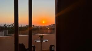 a view of a sunset from a balcony with a table at Sunset Sea View Retreat with pool in Kissonerga