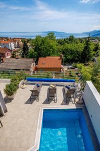 a swimming pool on a patio with chairs and a swimming pool at Apartments Bellavista in Matulji